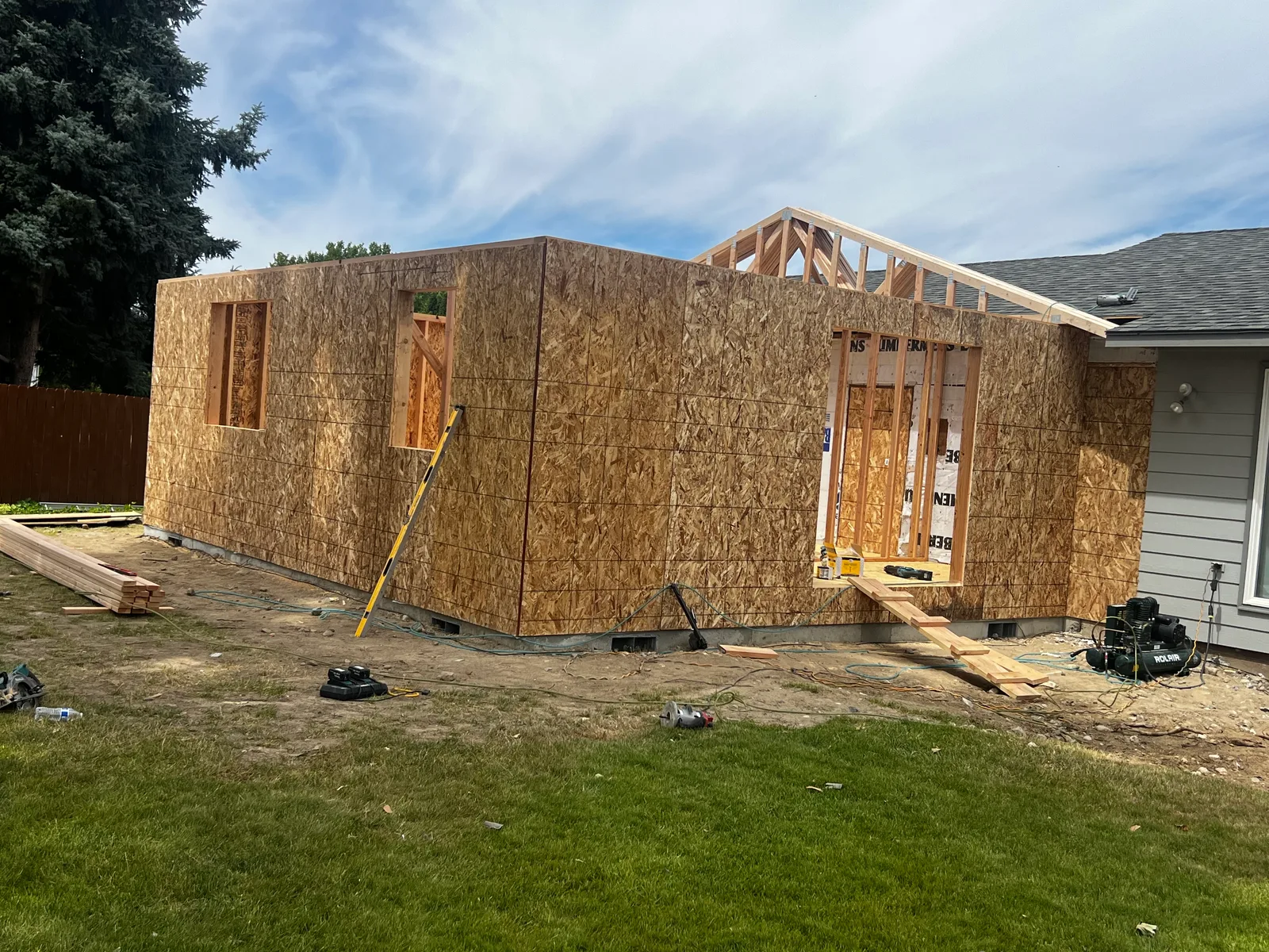 ADU framed in a backyard, mid-construction with window and door openings