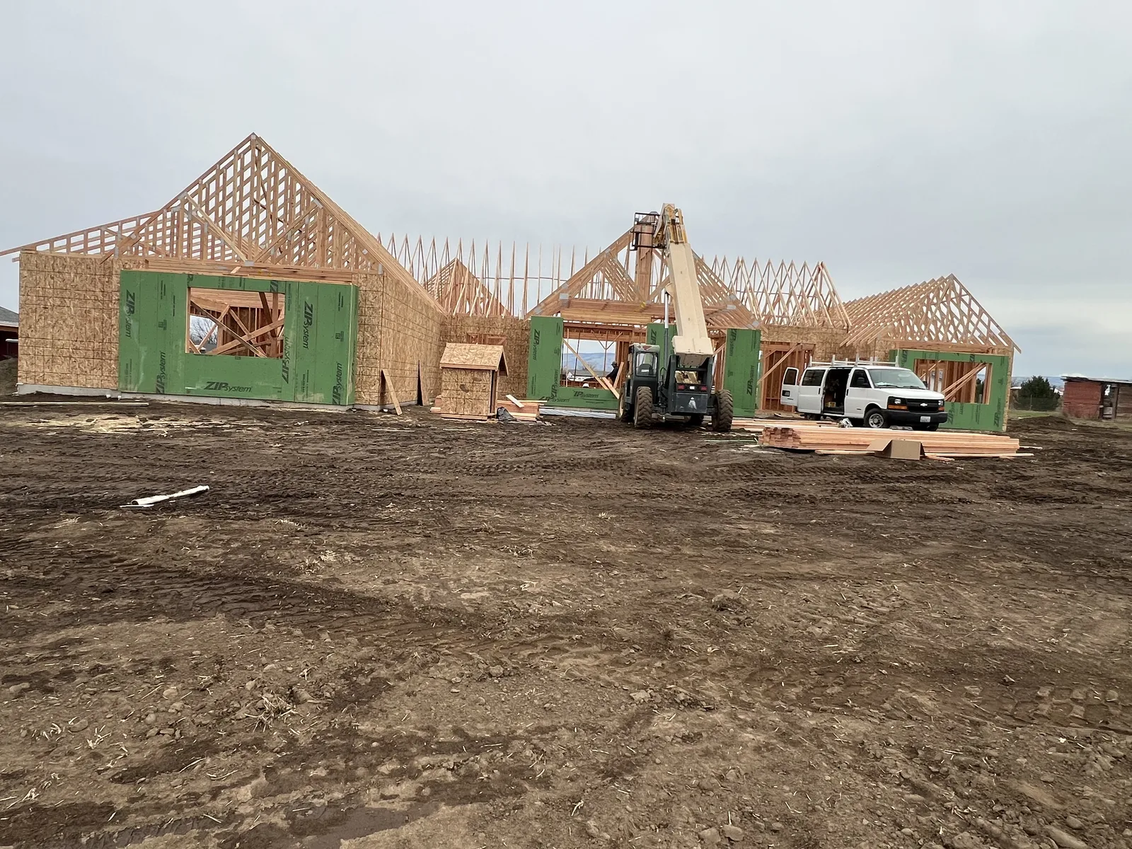 Multi-gable custom home wall framing with ZIP System sheathing and open roof trusses