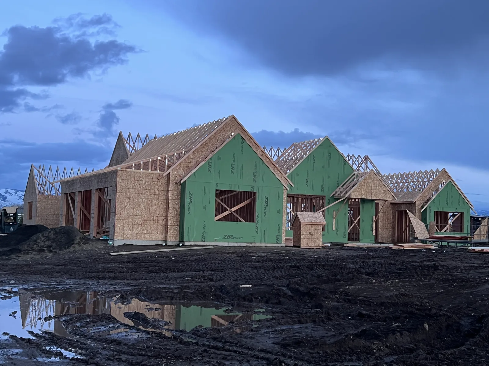 Dusk view of custom home gable framing with ZIP System sheathing reflected in a puddle