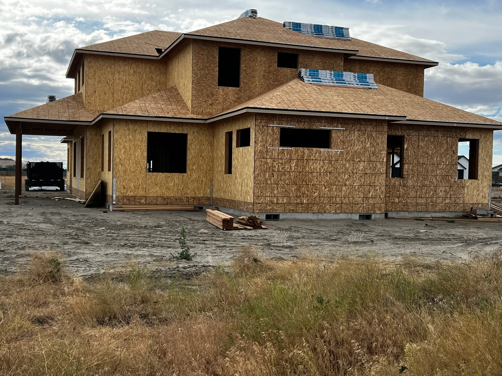 Large two-story custom home framed with roofing materials staged