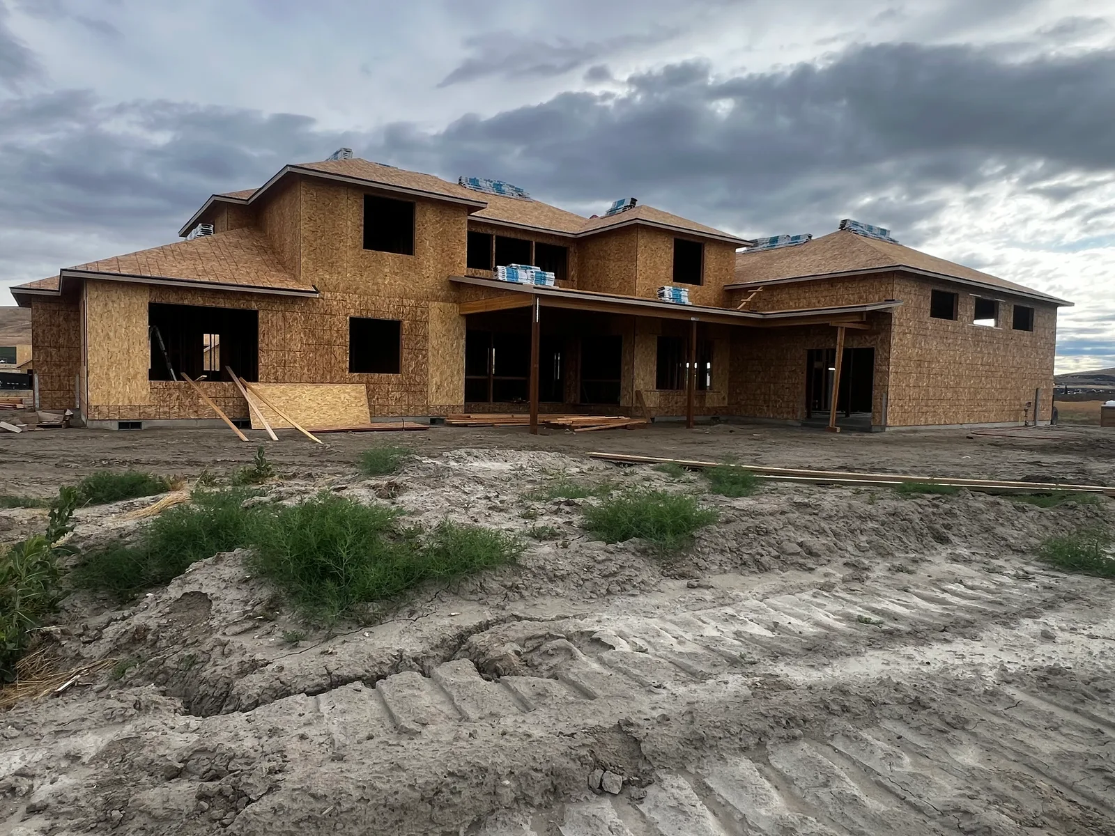 Two-story custom home framing under cloudy sky